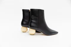 Botas cortas de cuero negro con punta fina y cierre lateral. Taco dorado con forma de esfera.