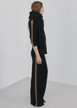 Pantalón de punto negro con diseño recto y holgado, con una franja lateral en tono marrón.