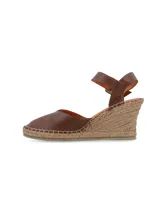 Sandalia de cuña Lora en cuero napa color marrón chocolate, con plataforma revestida en yute trenzado, puntera cerrada y tira ajustable al tobillo con hebilla forrada.