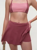 Falda short deportiva color bordó, con calza interna y bolsillo lateral, diseñada para brindar comodidad y libertad de movimiento.