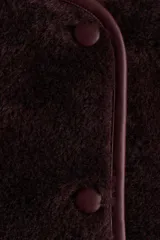 Campera de corte holgado confeccionada en sherpa suave, con escote redondo y cierre frontal de botones. Presenta hombros caídos, ribetes en tejido revestido y bolsillos laterales discretos.