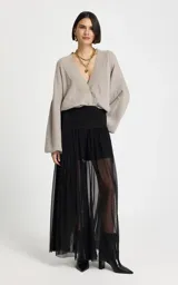 Pantalón de tiro alto confeccionado en tul negro, con silueta ajustada en la cadera y caída fluida. Presenta una cinturilla con detalle de aberturas horizontales y diseño de largo hasta el tobillo.
