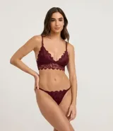 Conjunto de lencería de encaje rústico color bordó, compuesto por un bralette triangular con tirantes finos y una bombacha colaless de hilo doble con laterales ajustables.