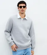 Buzo de moletón con felpa interna, color gris melange, con cuello polo blanco contrastante, mangas largas y terminaciones en rib en puños y cintura.