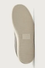 Zapatilla deportiva para hombre fabricada en piel con acabado en serraje, color gris. Presenta diseño liso con detalle de contraste en el talón en tono claro y suela de goma con volumen.