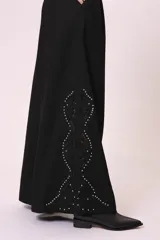 Pantalón palazzo negro con bordado de pequeñas tachas plateadas en forma de rombos a lo largo de la pierna.