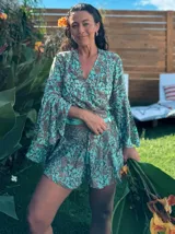 Conjunto de dos piezas compuesto por un top cruzado con mangas acampanadas y un short con cintura elástica y cordón ajustable. Presenta un estampado estilo paisley en tonos turquesa y marrón.