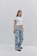 Jean de tiro medio con calce amplio y piernas wide leg, confeccionado en denim celeste con estampado floral. Cuenta con diseño de cinco bolsillos y cierre frontal con botón y cremallera.