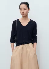 Jersey de punto fino color negro, con cuello en pico y manga larga. Presenta un diseño recto y minimalista.