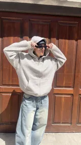 Campera con capucha y cierre frontal, de tejido grueso color gris oscuro con rayas horizontales finas en blanco. Presenta cuello alto y puños y cintura acanalados.