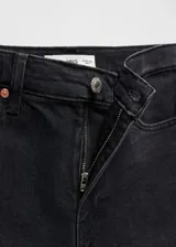Jeans estilo crop y corte slim de tiro medio, color negro, con diseño de cinco bolsillos, trabillas para cinturón y cierre frontal con cremallera y botón metálico.