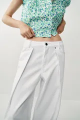 Jeans blancos de tiro medio y pernera ancha con corte barrel que se estrecha hacia el tobillo. Presenta cinco bolsillos, pliegues delanteros y cierre frontal con cremallera y botón metálico.
