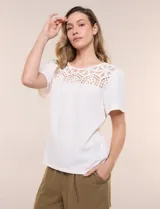 Blusa blanca de textura gofrada, de corte recto y semi holgado, con mangas cortas y escote redondo adornado con un canesú frontal en crochet calado.