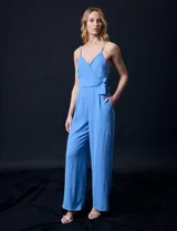 Enterito azul celeste de crepe, con escote cruzado en V, cintura elastizada y pierna ancha. Los tirantes son de cadena metálica.