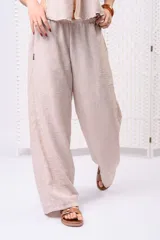 Pantalón palazzo de lino color beige, de tiro medio-alto, con cintura elastizada y silueta holgada de caída fluida.