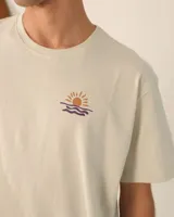 Remera unisex oversize color crudo con estampado pequeño en el pecho con un sol y olas. Corte holgado y mangas cortas.