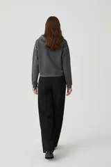 Canguro gris oscuro con capucha y cuello alto, decorado con tachas metálicas plateadas en los hombros y el cuello. De corte holgado y manga larga.