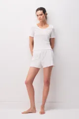 Remera de algodón blanca de manga corta, con diseño texturado, escote redondo y pequeño lazo decorativo en el centro. Presenta terminaciones con ondas en cuello, mangas y ruedo.