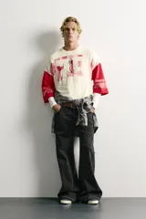 Camiseta boxy fit de cuello redondo y manga por debajo del codo. Presenta un diseño bicolor en tonos blanco off-white y rojo, con estampado y parches frontales con efecto lavado vintage y franjas en las mangas.