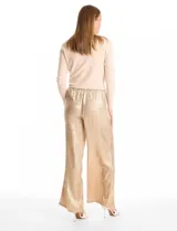 Pantalón de corte wide leg en tejido laminado metalizado color gris. Presenta pretina ancha elastizada con lazo de ajuste y bolsillos delanteros.