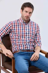 Camisa de corte sport con estampado de cuadros en tonos rojo, azul y blanco. Presenta cuello abotonado, cierre frontal con botones y bolsillo en el pecho con detalle bordado.