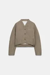 Chaqueta corta de corte estructurado confeccionada en tejido con mezcla de lana. Presenta cuello en pico, cierre frontal con botones y mangas largas. El diseño incluye bolsillos delanteros y un forro interior a contraste.