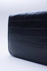 Billetera rectangular con cierre perimetral, confeccionada en cuero con textura de reptil. Cuenta con múltiples compartimentos internos para tarjetas, documentos y billetes, además de un bolsillo interior con cierre para monedas.