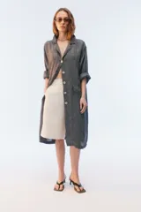 Tapado Aditi de lino con textura de microcuadrillé, calce oversize y largo midi. Cuenta con cuello y solapa, botones frontales, bolsillos con tapa y hombros caídos.
