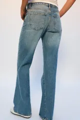 Jeans de tiro bajo con corte flare y diseño de cinco bolsillos. Presentan un acabado con efecto lavado y bajo evasé, con cierre frontal de cremallera y botón.