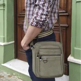 Morral de lona color verde militar, con compartimento principal con cierre superior y múltiples bolsillos frontales con cierre. Cuenta con correa ajustable tipo galón para llevar al hombro o cruzado.