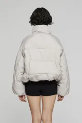 Campera tipo bomber acolchada, color negro, con cuello alto, cierre frontal con cremallera y diseño de mangas amplias.