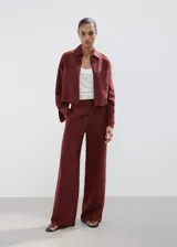 Pantalón de tiro medio color bordó, de corte recto y pernera ancha, con bolsillos laterales, trabillas y cierre de lazo en la cintura.