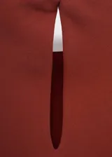 Blusa color bordó con hombreras marcadas, cuello barco y diseño recto sin mangas.