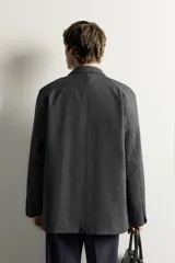 Blazer regular fit de color gris oscuro, confeccionado en tejido con estructura, con cuello de solapas de muesca, cierre frontal con botones y bolsillos plastrón con solapa en el delantero.