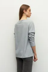 Remera negra de manga larga, cuello alto y corte diagonal en la parte inferior.