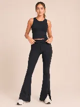 Conjunto deportivo compuesto por un top básico sin mangas de cuello redondo y una calza acampanada de tiro alto con aberturas laterales en el ruedo. Ambas piezas son de color negro y presentan un diseño minimalista.