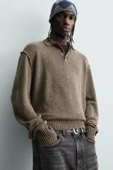 Polo de punto con cuello solapa y cierre frontal de tres botones. Presenta un diseño de manga larga con acabado en rib en puños y cintura, en un tono marrón jaspeado.