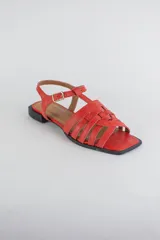 Sandalias de cuero color negro, de suela plana, con tiras entrelazadas en la capellada y tira ajustable en el talón con hebilla metálica.