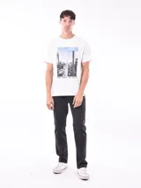 Remera blanca de manga corta con cuello redondo y un estampado fotográfico de una ciudad con rascacielos en el centro del pecho.