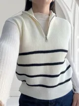Chaleco de punto color crudo con rayas horizontales negras, cuello polo con cierre metálico y corte holgado.