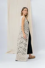 Chaleco largo tejido en punto calado color beige, de silueta recta y caída fluida. Presenta un diseño artesanal con transparencias sutiles que aportan textura y movimiento.