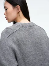 Sweater de tejido suave en tono beige melange, con cuello redondo, mangas largas y corte relajado.