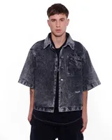 Camisa de denim negra con efecto lavado, corte recto, mangas cortas y bolsillo en el pecho.