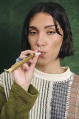 Buzo de manga larga con diseño patchwork que combina diferentes texturas y estampados, incluyendo tejido waffle verde oliva, tejido a rayas y cuadros en tonos grises y marrones, unidos con costuras visibles.