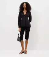 Blazer sastre Blue Steel de color negro, confeccionado en poliéster con elastano y forro de poliéster. Presenta un diseño estructurado con escote en V pronunciado, cierre frontal de un botón y bolsillos con solapa en los laterales. Las mangas largas tienen volumen tipo cocoon.