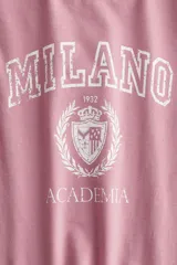 Remera de algodón de corte entallado, con cuello redondo y mangas cortas. Presenta un estampado frontal con la inscripción 'MILANO ACADEMIA' y un escudo universitario.