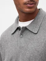 Buzo tipo polo de tejido suave, con cuello clásico, cierre frontal de botones y puños y ruedo acanalados.