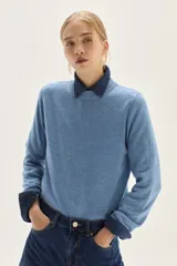 Sweater de punto color beige, con cuello redondo, manga larga y puños acanalados.