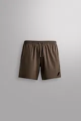 Short deportivo Zara Athleticz de color marrón, confeccionado en tejido técnico ligero y elástico con forro interior. Cuenta con cintura elástica ajustable con cordón, bolsillos frontales, bolsillo trasero con cierre de cremallera, bajo con aberturas laterales y detalle de logo estampado en la pierna.