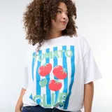 Camiseta blanca de corte oversize y manga corta con diseño estampado de rayas verticales celestes, tomates y la inscripción 'Tomato Club'.